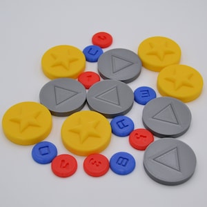 May include: A collection of yellow, gray, and blue game pieces. The yellow pieces have a star design, the gray pieces have a triangle design, and the blue pieces have a square design.