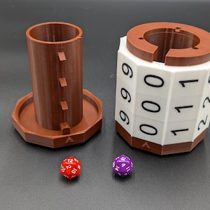 May include: A brown plastic dice tower with a white base and a removable cylinder. The tower has six sides with numbers 0, 1, and 2 printed on each side. There are two dice, one red and one purple, on a gray surface.