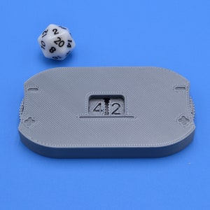 May include: A gray 3D printed counter with a slot displaying the number "42".