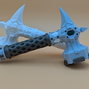 May include: A light blue and gray fantasy hammer with a textured, dark green handle. The hammer head has a stylized design with a gem-like accent. A second hammer is visible in the background.