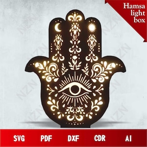 Peut inclure: Une boîte lumineuse en forme de main de Hamsa marron avec des motifs découpés complexes. Le design comprend une lune, un soleil, un œil et des motifs floraux. Le texte "Hamsa light box" est en haut à droite. Options de fichiers: SVG, PDF, DXF, CDR, et AI en bas.