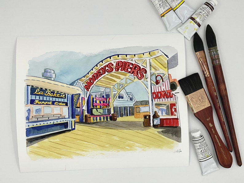May include: A watercolor painting of a boardwalk scene with a red and white striped awning that reads "Mooey's Piers". There is a blue and yellow building with the text "La Bakerie" and "Sweet Treats" on the left side of the image.