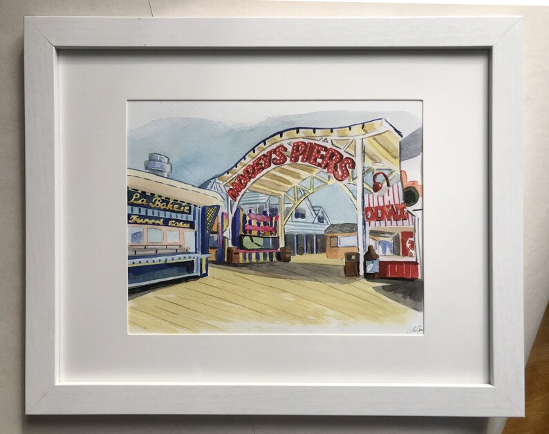 May include: Watercolor painting of a boardwalk scene with a red and white sign that reads "Audrey's Piers". There are several shops and food stands on the boardwalk, including one that says "La Bake-it" and another that says "Chill Zone".