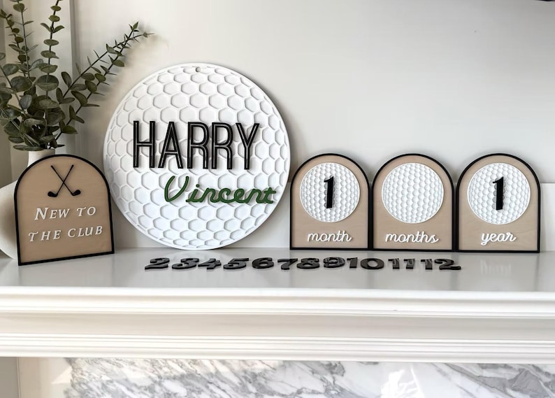 May include: A circular white golf ball textured sign with the black text HARRY and green text Vincent, alongside three arched signs with golf ball textures, black numbers, and the text New to the club, month, months, year, plus loose black numbers.