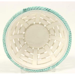 May include: A round ceramic bowl with a white woven basket-weave pattern and a solid circular base. The rim features a textured, rope-like design painted in a light turquoise blue color, contrasting with the smooth white interior surface.