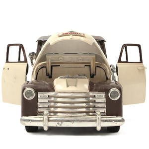 May include: A vintage brown and cream-colored Chevrolet pickup truck model with the hood and doors open. The chrome grill and headlights are visible, and the word "CHEVROLET" is displayed on the hood.