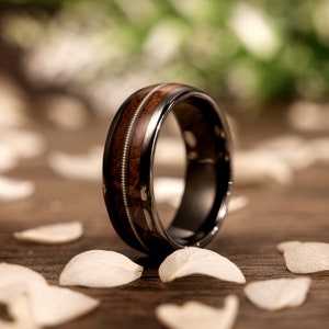 May include: A black and brown ring with a wood inlay. The ring is made of tungsten carbide and has a polished finish.