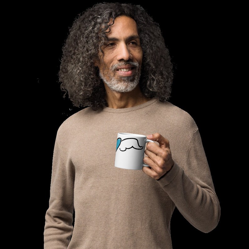 May include: A man with long, gray hair is holding a white mug with a blue heart and a black mustache design.