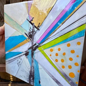 May include: Abstract painting on a square canvas with a central image of a utility pole with wires and a bird's nest. The background is a mix of geometric shapes in shades of blue, green, pink, and gold. The painting is signed in the lower right corner.