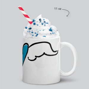 May include: White ceramic mug with a black line drawing of an elephant with a blue heart. The mug is filled with whipped cream and blue sprinkles. A red and white striped straw is in the mug. The mug is 11 oz.