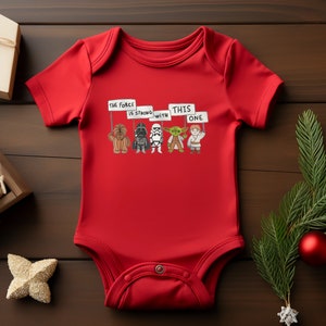 May include: Red baby onesie with a graphic of Star Wars characters holding signs that say "The Force is Strong with This One".
