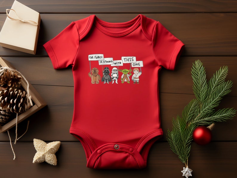 May include: Red baby onesie with a graphic of Star Wars characters holding signs that say "The Force is Strong with This One".