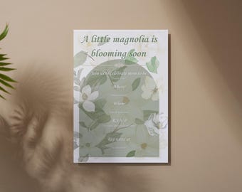May include: A white invitation card with a magnolia flower design. The text reads "A little magnolia is blooming soon" and "Join us to celebrate mom to be". The card is on a beige background.
