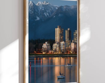 May include: A framed photograph of a city skyline with tall buildings and a mountain range in the background. The city is lit up at night, and there are two sailboats in the water in the foreground.