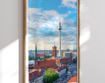 Puede incluir: Una fotografía enmarcada del horizonte de Berlín con la icónica torre de televisión Fernsehturm en el centro. La foto muestra una mezcla de edificios modernos e históricos, incluyendo el ayuntamiento de ladrillo rojo Rotes Rathaus.