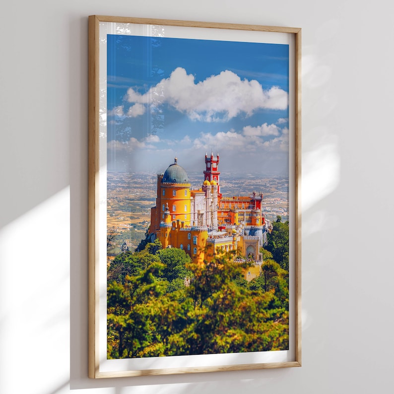 May include: A yellow and red castle with a blue sky and white clouds in the background. The castle is surrounded by green trees.