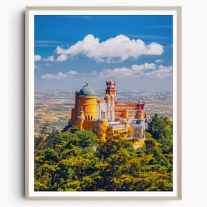 May include: A yellow and red castle with a blue domed roof sits on a hilltop overlooking a green forest and a distant city. The sky is blue with a large white cloud.