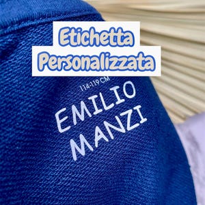 Pode incluir: Uma peça de tecido azul profundo com o texto impresso em branco EMILIO MANZI e a medida 114-119 CM. Uma sobreposição retangular branca com o texto azul Etichetta Personalizzata está posicionada sobre a parte superior do tecido azul.