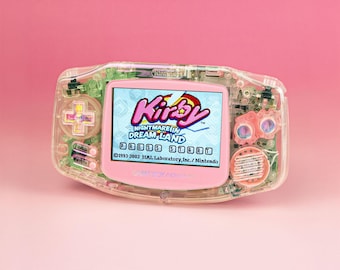 May include: A transparent Game Boy Advance handheld console with internal green circuitry visible. The screen displays the title Kirby Nightmare in Dream Land with the text Press Start and copyright information from 1993-2002 HAL Laboratory, Inc. Nintendo.