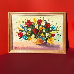 May include: Oil painting of a floral arrangement in a gold-toned frame. The bouquet features red, yellow, and blue flowers in a yellow vase. The artist's signature, "КлименкоТ", is visible in the lower left corner. The background is a light yellow.