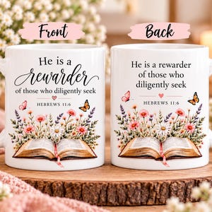 May include: A white ceramic mug featuring a floral illustration with an open book, butterflies, and the text 'He is a rewarder of those who diligently seek' along with 'HEBREWS 11:6'. The design is shown from two angles, labeled as front and back.