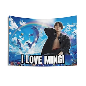 Op de afbeelding: Een blauwe en witte wandkleed met een man in een zwart jack en een blauwe dolfijn. De tekst "I LOVE MINGI" is op de wandkleed gedrukt.