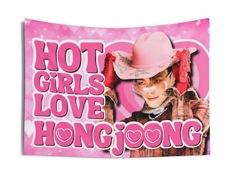 May include: Pink tapestry with the text "HOT GIRLS LOVE HONGJOONG" in a bubble font. The tapestry features a person wearing a pink cowboy hat, red gloves, and a plaid shirt. The background is pink with heart shapes.