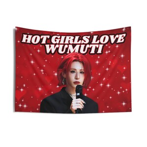 Könnte beinhalten: Ein rotes Wandbehang mit dem Text "HOT GIRLS LOVE WUMUTI" in Weiß. Der Wandbehang zeigt eine Person mit roten Haaren, die ein Mikrofon hält, vor einem roten Hintergrund mit Herzen und Sternen.