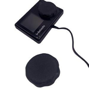 Könnte beinhalten: Eine schwarze Actionkamera mit einer schwarzen Objektivabdeckung und einem schwarzen Kabel. Die Kamera hat einen kleinen Bildschirm und den Text "Jebasto" auf der Vorderseite. Eine zweite schwarze Objektivabdeckung ist separat abgebildet.