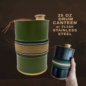 Puede incluir: Dos cantimploras de tambor de acero inoxidable, una verde oliva y otra negra, con bandas tejidas. La cantimplora verde tiene una banda beige con ribete negro y blanco. El texto dice "25 OZ DRUM CANTEEN or FLASK STAINLESS STEEL."