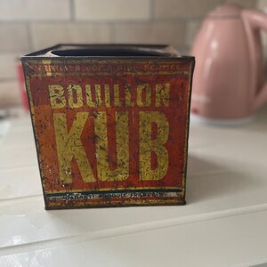Puede incluir: Caja de metal vintage con una etiqueta roja y amarilla que dice "Bouillon Kub" y "Garanti Produit Francais".