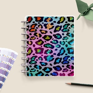 May include: A rainbow-colored notebook with a glitter leopard print design. The notebook has a silver ring binder and is closed.