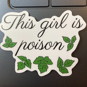 May include: White sticker with the text "This girl is poison" in black cursive font. Five green leaf illustrations surround the text.