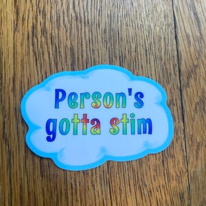 May include: A blue cloud-shaped sticker with the text "Person's gotta stim" in rainbow colours.