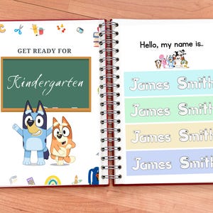 Op de afbeelding: Een blauwe en oranje cartoon hond en kat staan voor een schoolbord met de tekst "Get Ready for Kindergarten". De pagina is uit een spiraalgebonden boek met de tekst "Hello, my name is..." en vier regels om een naam te schrijven. De regels zijn in blauw, groen, geel en lichtblauw.