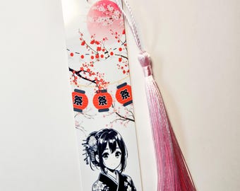 May include: A rectangular bookmark featuring a Japanese anime-style illustration. The design includes a girl in a kimono, cherry blossoms, red lanterns with Japanese characters, and a pink tassel. The bookmark is white with a pink and white tassel.