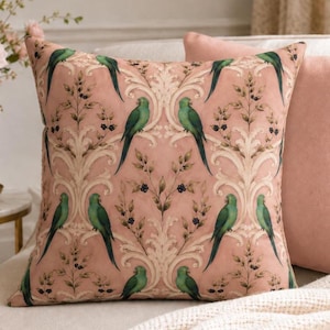 May include: A square throw pillow featuring a dusty pink background with a repeating pattern of green parrots perched on cream-coloured scrolling acanthus leaves and delicate branches with small dark berries, creating a symmetrical botanical design.