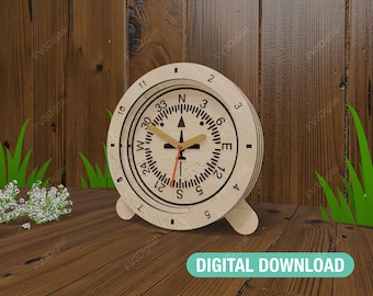 Op de afbeelding: Een houten klok met een kompasontwerp. De wijzerplaat heeft zwarte cijfers en markeringen, met een rode secondewijzer en bruin gekleurde uur- en minutenwijzers. De klok staat op een houten oppervlak met groen gras en witte bloemen. De tekst "DIGITAL DOWNLOAD" staat onderaan.