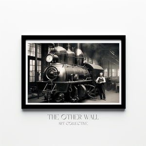 Könnte beinhalten: Ein Schwarzweißfoto einer alten Dampflokomotive in einem Bahndepot. Ein Mann steht neben der Lokomotive und schaut in die Kamera. Der Text "THE OTHER WALL ART COLLECTIVE." ist unter dem Bild gedruckt.