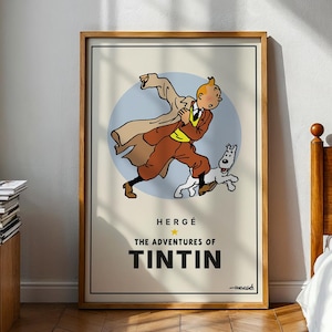 May include: A framed poster featuring a cartoon illustration of Tintin running with his dog Snowy. The poster has a light beige background with a blue circle behind the characters. The text "HERGÉ THE ADVENTURES OF TINTIN" is displayed below the illustration.