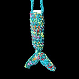 May include: A turquoise crochet lip balm holder with a mermaid tail design. The holder is made of colorful yarn with pink, yellow, and red accents. The holder has a turquoise strap for carrying.