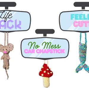 May include: Image features three car mirror-shaped signs with text: "Life Hack", "No Mess Car Chapstick", and "Feelin' Cute". Each sign has a crocheted item hanging below: a mouse, a mushroom, and a mermaid tail. The background is white.