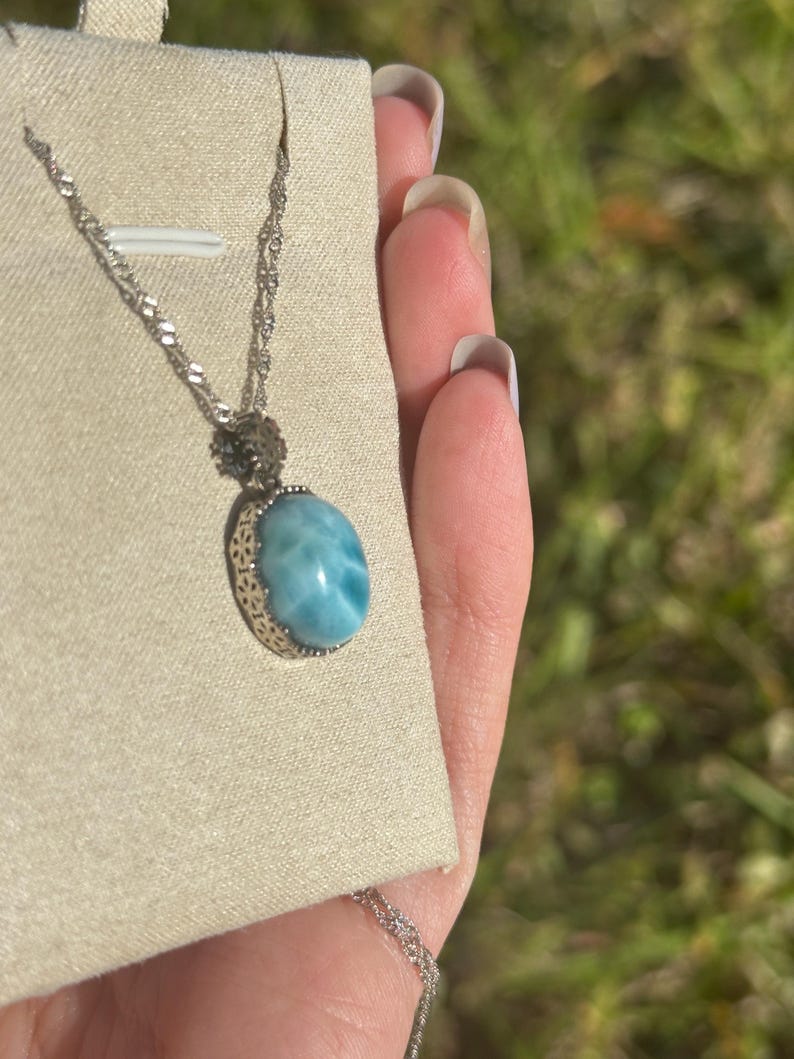 Pode incluir: Um colar de corrente de prata com um pingente oval azul e branco com um padr&atilde;o de redemoinho. O pingente &eacute; engastado em uma moldura de filigrana de prata.