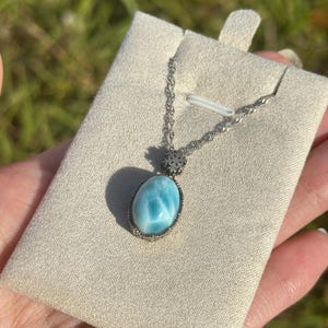 Pode incluir: Um colar de corrente de prata com um pingente oval azul e branco. O pingente &eacute; engastado em um bezel de prata e tem um delicado charme de floco de neve de prata.