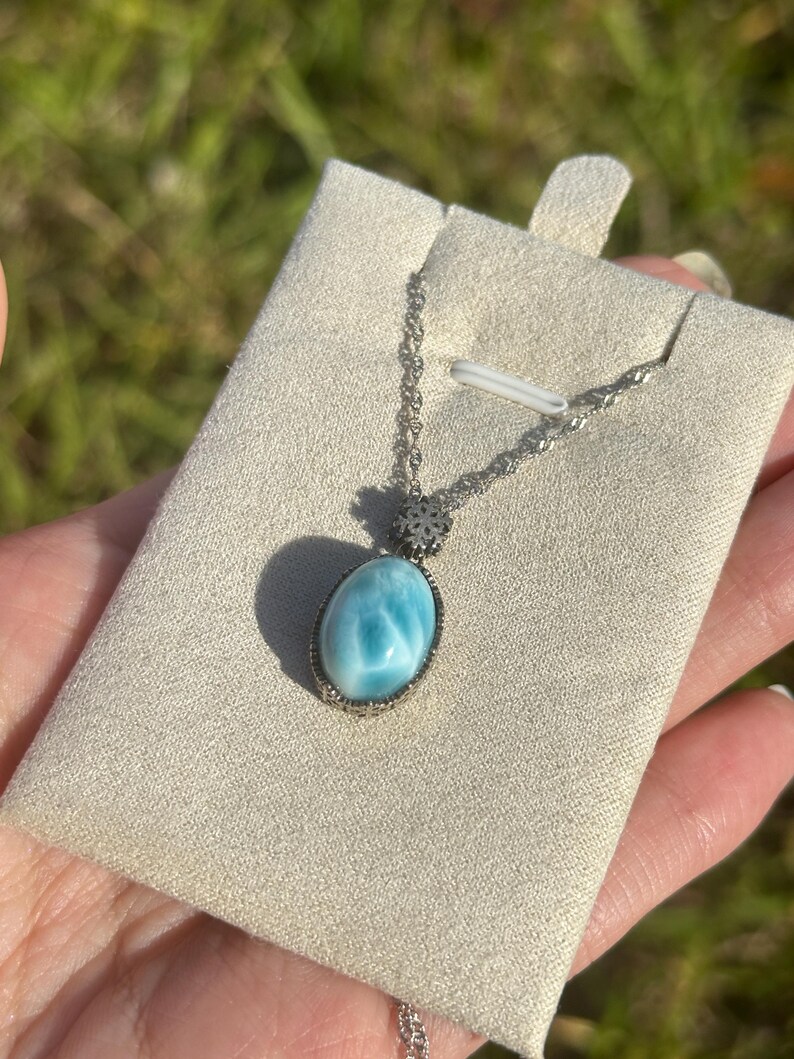 Pode incluir: Um colar de corrente de prata com um pingente oval azul e branco. O pingente &eacute; engastado em um bezel de prata e tem um delicado charme de floco de neve de prata.