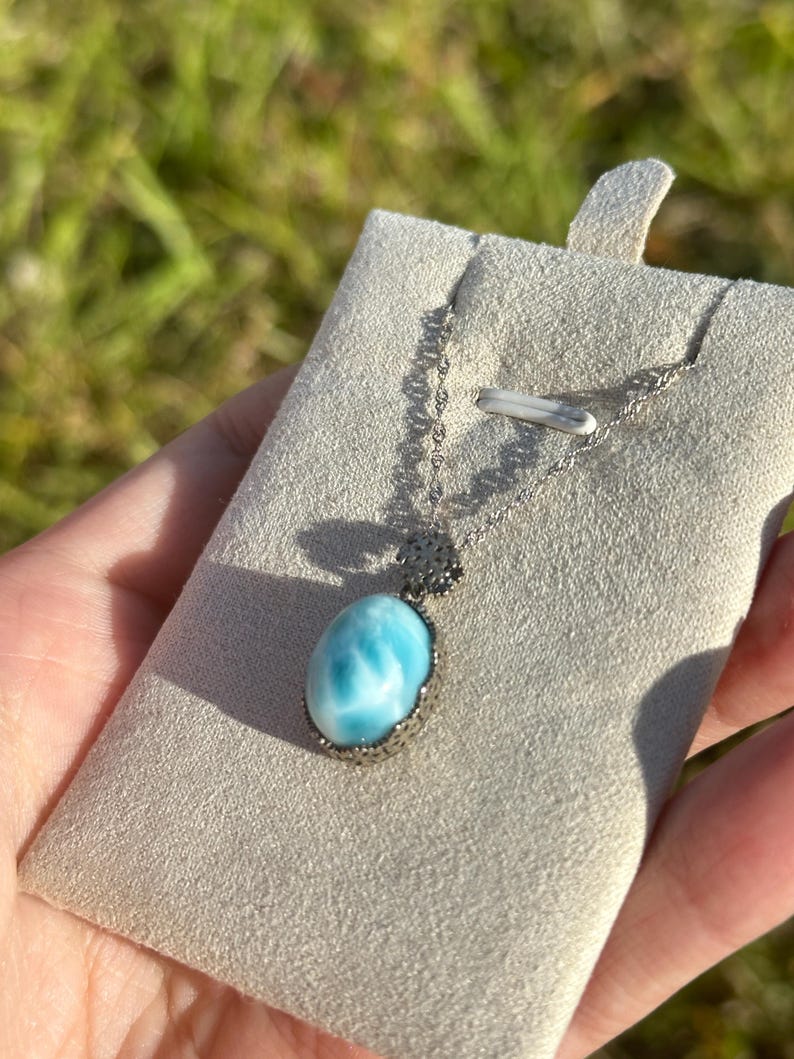 Pode incluir: Um colar de corrente de prata com um pingente oval azul e branco. O pingente &eacute; engastado em uma moldura de prata e tem um design delicado e intrincado.