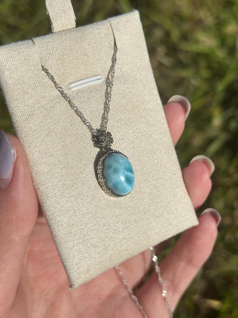 Pode incluir: Um colar de corrente de prata com um pingente oval azul e branco engastado em uma moldura de filigrana de prata.