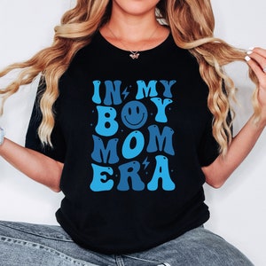 May include: Black t-shirt with a blue and white graphic that says "In My Boy Mom Era" with a smiley face in the middle.