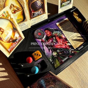 Può includere: Primo piano di un tabellone da gioco con carte, dadi e gettoni. Il tabellone è nero con un design viola e bianco. Le carte sono di diversi colori e hanno immagini di persone e oggetti. I dadi sono rossi, blu e gialli. I gettoni sono monete d'oro.