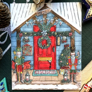 Peut inclure: Illustration de Noël avec une maison à la porte rouge, une couronne et deux casse-noisettes. La maison a un extérieur bleu et est décorée de guirlandes et d'un petit sapin de Noël. Le paillasson dit "HO! HO! HO!"